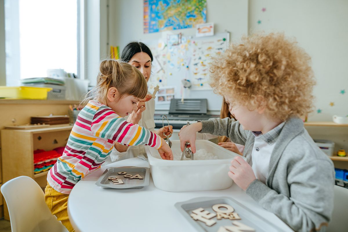 Two children playing with their teacher at school