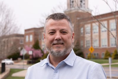 A photo of Matthew Hilliard with Marsh Hall's bell tower in the background.