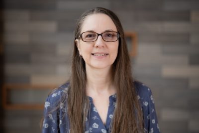 Karen Oaks standing in front of a gray wall in University Point