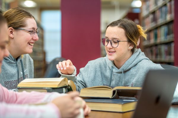 Three girls reading books in the library