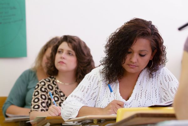 Two students writing at their desks during a lecture