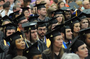 A group of graduates sitting at commencement listening to the ceremony