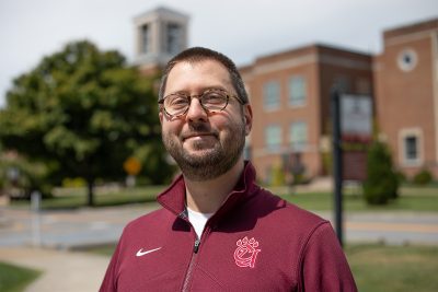 A photo of Andy Blum in front of the Concord University Bell Tower