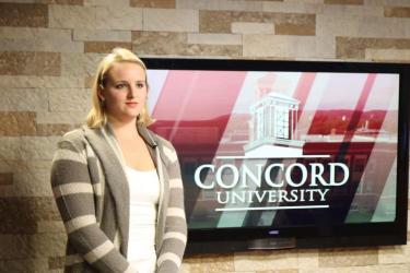A student standing next to a screen in preparation for Mountain Lion News