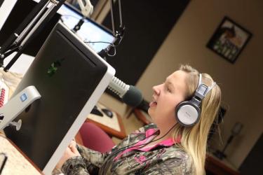 A student wearing a headset and speaking into a microphone