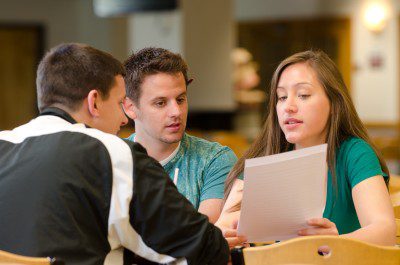 Three Social Work students gathered together discussing a paper.