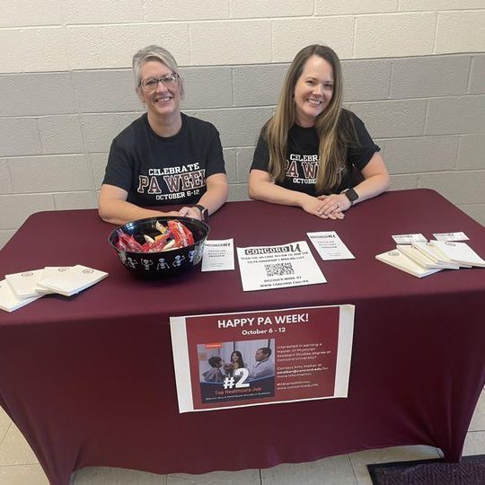 Professor Staci Linkous and Amy Walker seated behind PA Information Booth