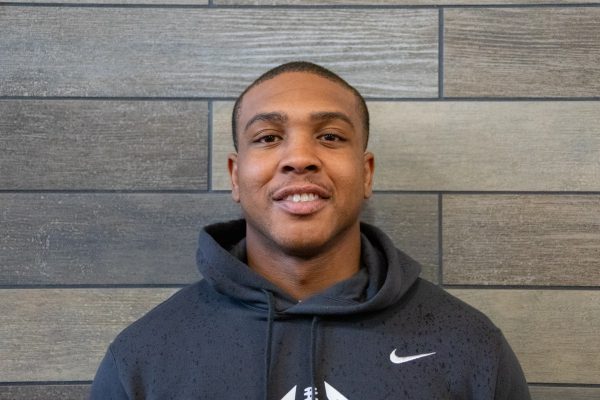 A photo of Christopher Anderson standing in front of a gray slate tile wall.