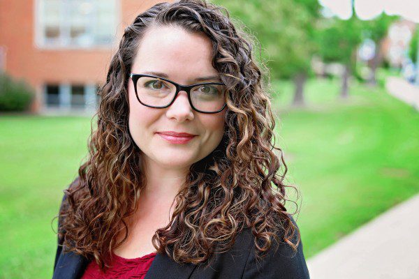 A photo of Beth Sampson, our Academic Coordinator, with the campus greenery in the background