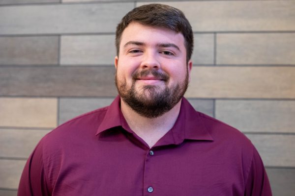 A photo of Jacob Harmon in front of a gray slate wall