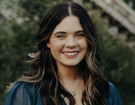 A photo of Madeline Hawkins in front of greenery