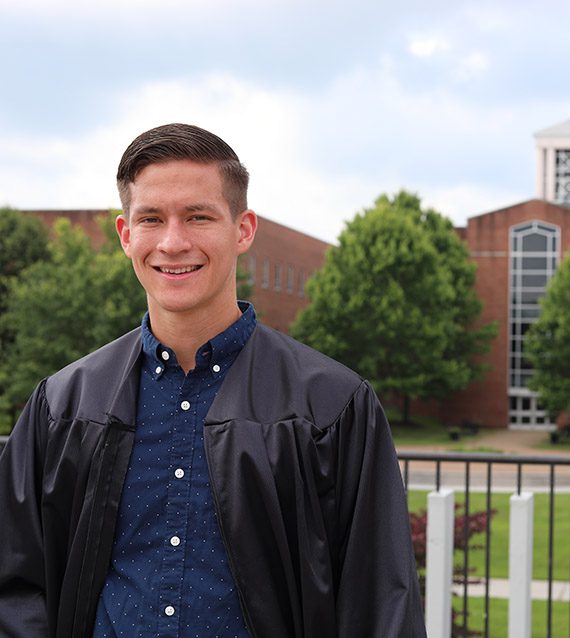 A photo of Adam Cook in front of the Concord University Bell Tower