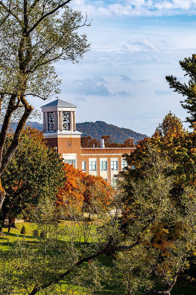The Concord University bell tower as seen through some tall autumn trees