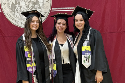 Three CU Social Work grads posing in their regalia at commencement