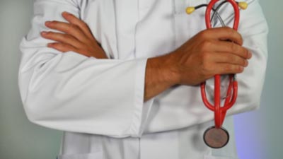 A doctor with their arms crossed holding a stethoscope