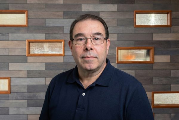 Sid standing in front of a gray slate wall in University Point