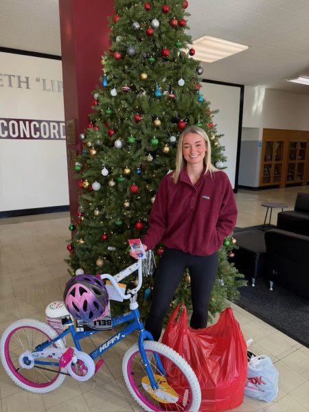 A nursing student stands with the bicycle that the Society of Nursing Majors donated to the Salvation Army Angel Tree.