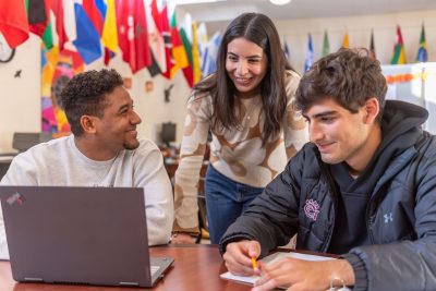 Three students working on homework while talking and laughing in the Office of Multicultural Affairs