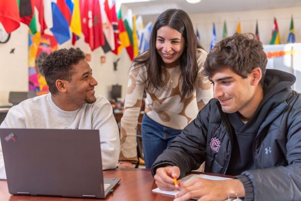 Three students working on homework while talking and laughing in the Office of Multicultural Affairs