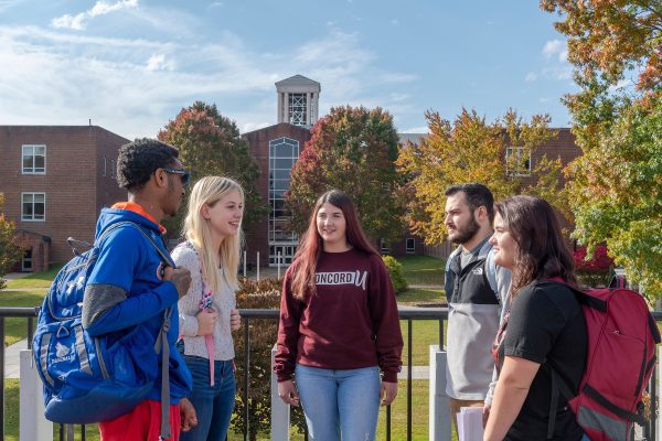 A group of students standing & talking on the Alexander Fine Arts Center balcony