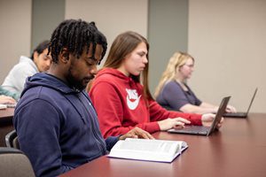 Students working on laptops and reading textbooks while in class